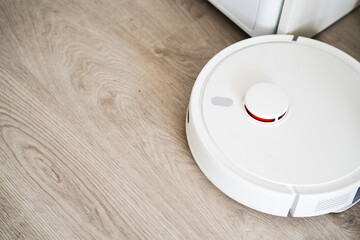 Top view of robot vacuum cleaner on wooden floor showing round design and bright interior setting