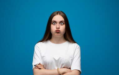 Expressive young woman posing with a confused facial expression against a bright blue studio background