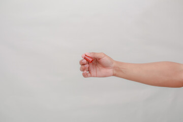 Hand holding a red push pin against a neutral background ready for use
