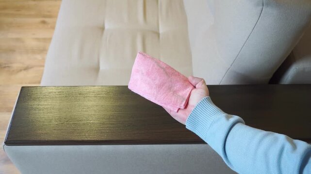 A man wipes a dusty sofa armrest. Wet cleaning of the house. Home cleaning concept 