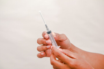 Hands holding a syringe with needle poised for injection or medical procedure