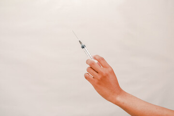 A hand holds a syringe ready for an injection representing vaccination and healthcare