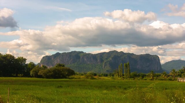 Time-lapse of clouds drifting over green rice fields and forested hills in rural Indonesia  showcasing nature&rsquo;s peaceful movement,Phu Pha Man, Khon Kaen, Thailand.