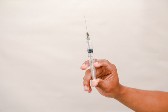 A hand holds a clear syringe ready for injection representing medical care and vaccination - Powered by Adobe