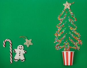 A gingerbread man with a cane is depicted on a green background, with sugar stars scattered in the shape of a Christmas tree. Christmas background