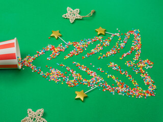 Christmas background. Sugar stars scattered across a green background in the shape of a Christmas tree. Top view, flat lay