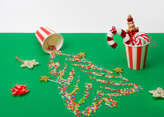 Christmas background. Sugar stars shaped like a Christmas tree are scattered across a green background, along with Christmas tree ornaments