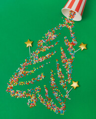 Christmas background. Sugar stars scattered across a green background in the shape of a Christmas tree. Top view, flat lay