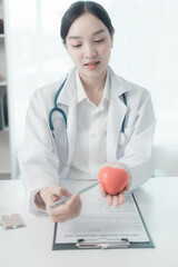 Smiling young female doctor holding a red heart. Concept of love, health and insurance. Healthcare...