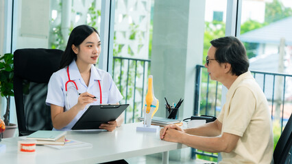 Asian female doctor talking to senior male patient giving advice about body pain. Medical personnel recording medical history.