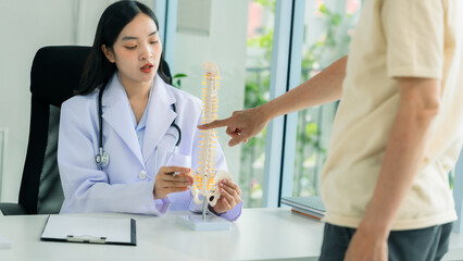 Asian female doctor talking to senior male patient giving advice about body pain. Medical personnel recording medical history.