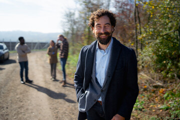 Group of people engaging in conversation outdoors in a sunny setting near a road