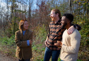 Friends enjoy a sunny autumn day while chatting and laughing in a forested area