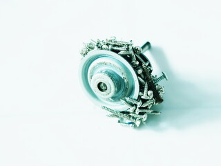 The image shows a strong magnet attracting a large number of metal screws.