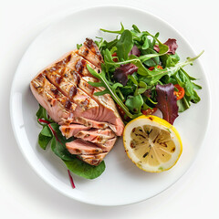 Perfectly grilled salmon fillet sliced and served with fresh mixed green salad and a bright lemon half, isolated on white background