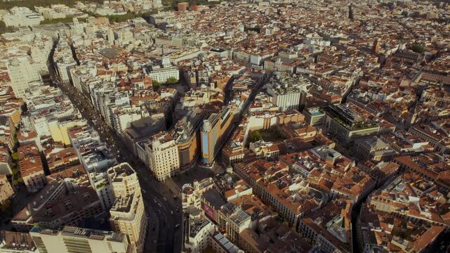 Stunning aerial drone footage slowly zooming in on the iconic Gran V&iacute;a and Plaza del Callao in Madrid, Spain, during a beautiful golden hour sunset.