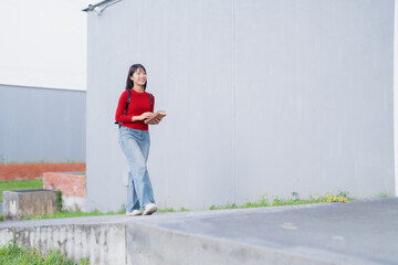 Fototapeta premium Asian student walking on campus carrying books