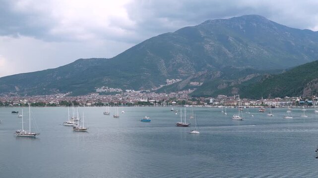 Aerial view of Fethiye marina and harbor in Turkey with numerous yachts, sailboats, and gulet boats anchored in bay with mountains