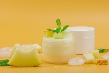 Natural melon hydrating cream with mint and ice pieces. White cosmetic jars and fresh fruit