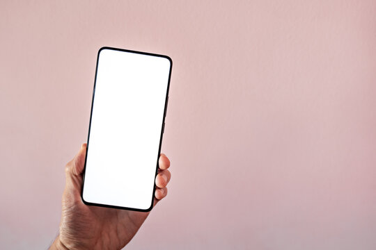 smartphone with blank screen held in hand. hand holding blank mobile screen placed on table, frameless modern design - Powered by Adobe