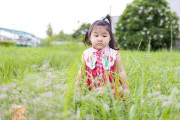 A cute little Asian girl is having fun chasing butterflies in the grass.