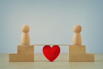 Two distant wooden pawns joined by a brige with heart - Concept of love and distance