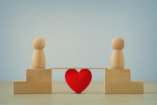 Two distant wooden pawns joined by a brige with heart - Concept of love and distance