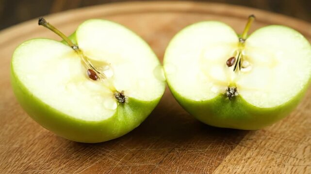 A close-up shot of two halves of a cut green fruit with seeds on a wooden surface