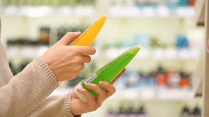 Woman comparing body wash or shower gel in a store aisle, reading cosmetic labels and ingredients to choose the best skincare product.