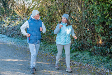 happy senior couple jogging on frosty path, cool weather, morning jog, active lifestyle, healthy enjoying active aging together sports, fitness during, healthier routine in nature, daily exercise