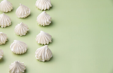 Fresh homemade meringue cookies over green background with copy space