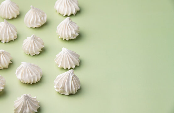 Fresh homemade meringue cookies over green background with copy space