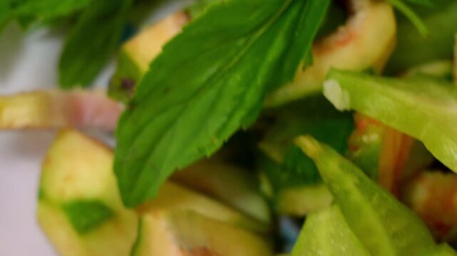 A plate of sliced green figs and sour starfruit with fresh herbs, served alongside a bowl of spicy fermented dipping sauce.