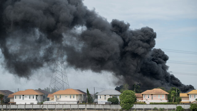 Dramatic scene of thick black smoke billowing over a residential neighborhood