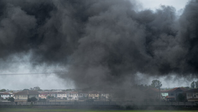 Dramatic view of thick black smoke billowing over a residential area