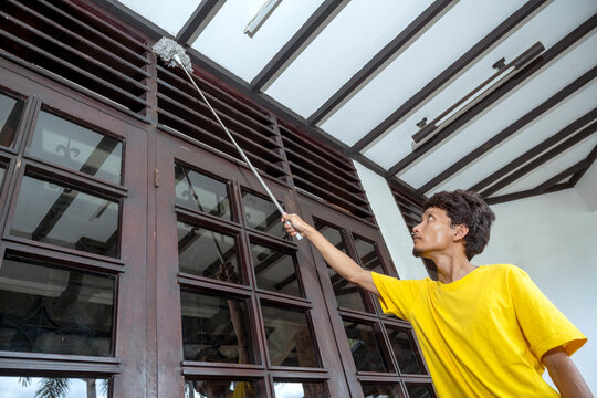 Man in a yellow shirt is cleaning a window with a squeegee. Cleaning concept