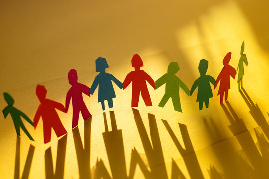 Community, paper humans holding hands together, Diversity and Inclusion concept on yellow background. United different people standing together.