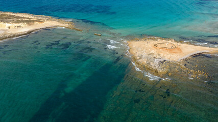 Obraz premium Aerial view of the isthmus separating Isola delle Correnti from Sicily, Italy. The sea is clean and crystal clear. It is the southernmost point of Italy. It is a sunny summer day.