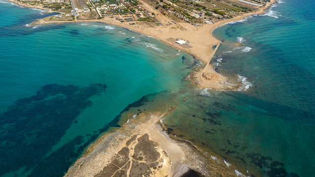 Aerial view of the isthmus separating Isola delle Correnti from Sicily, Italy. The sea is clean and crystal clear. It is the southernmost point of Italy. It is a sunny summer day.