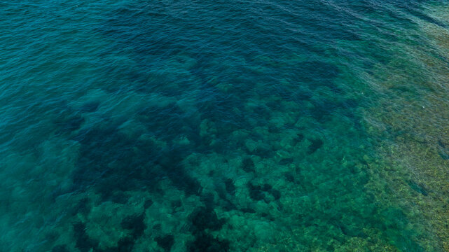 Aerial perpendicular view of the sea surface. The ocean's colors range from turquoise to blue. Ideal for backgrounds, textures and patterns.