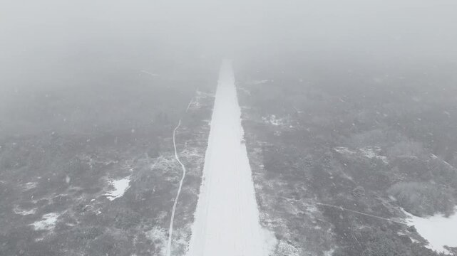 Aerial moving forward at a level flight toward the end of a snow-covered abandoned Killaloe/Bonnechere Airport runway in winter