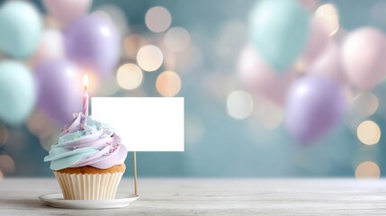 Birthday cupcake with a lit candle and blank note card on a white wooden table, celebrating a special occasion