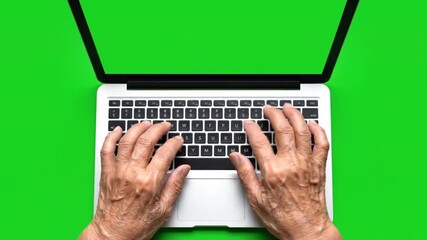 Overhead view of elderly persons hands typing on a laptop keyboard with a green screen background - Powered by Adobe