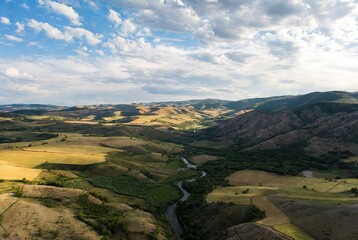Naklejka premium Rural landscape with winding river and rolling hills, blue sky
