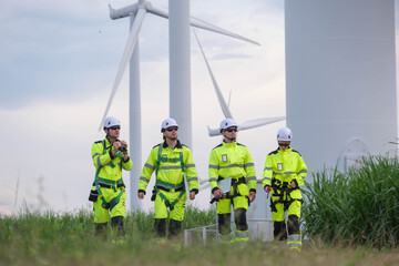 Workers in bright uniforms walking near wind turbines during afternoon at a renewable energy site...