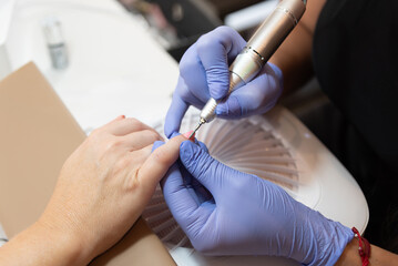 Manicurist performing nail care with electric drill
