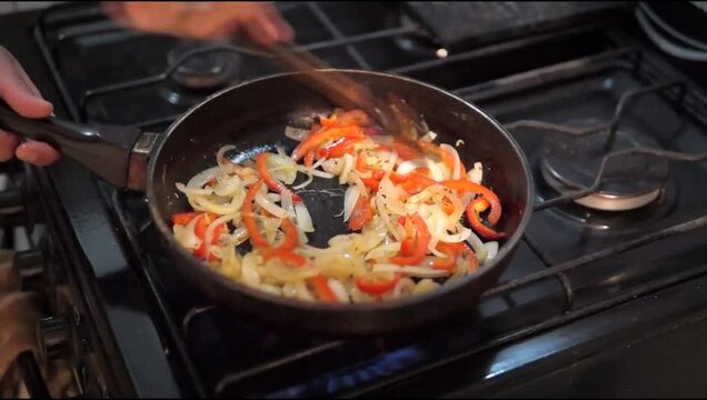 peper and onion being cooked in a frying pan