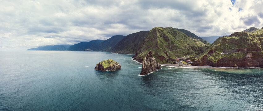 Panoramic drone view of rugged sea stacks at Ribeira da Janela on Madeira Island Portugal, showing vast Atlantic waters meeting lush green cliffs