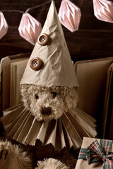 Portrait of vintage style teddy bear in paper ruff collar and a cap with a gift box in sepia color