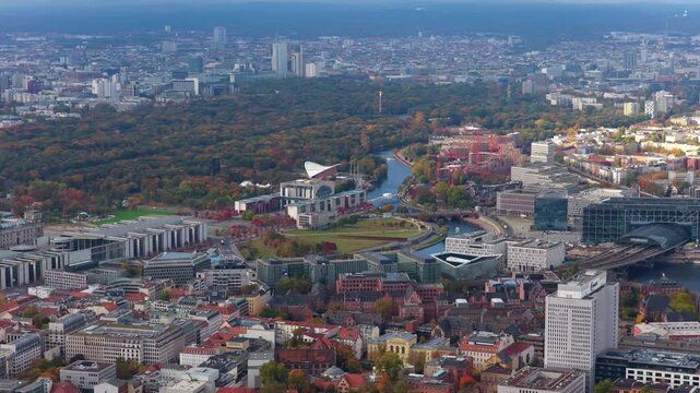 High altitude footage flying over Berlin, showing capital's skyline with government district, Hauptbahnhof Central Train Station, autumn colors in Tiergarten park
